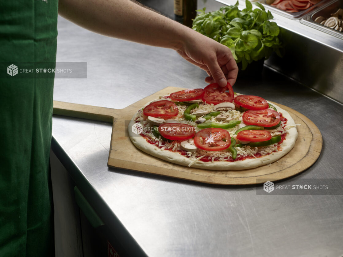 A cook preparing a small veggie pizza