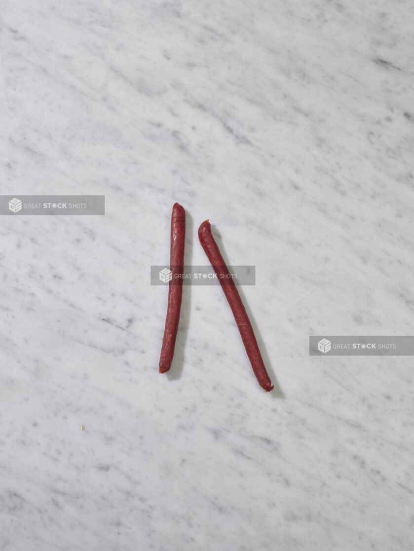 Thin pepperette sausages on a marble background