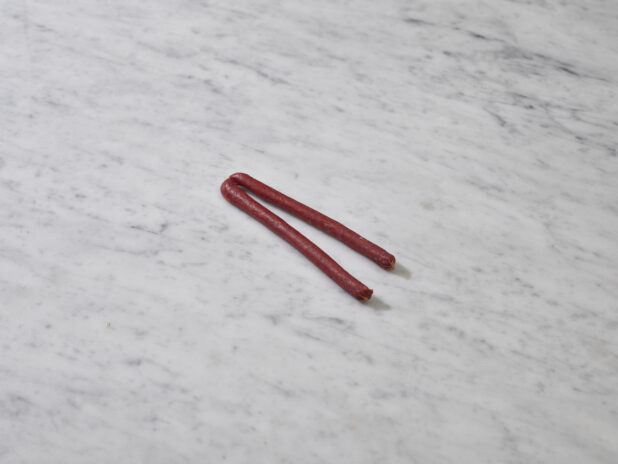 Whole pepperette sausages on a marble background