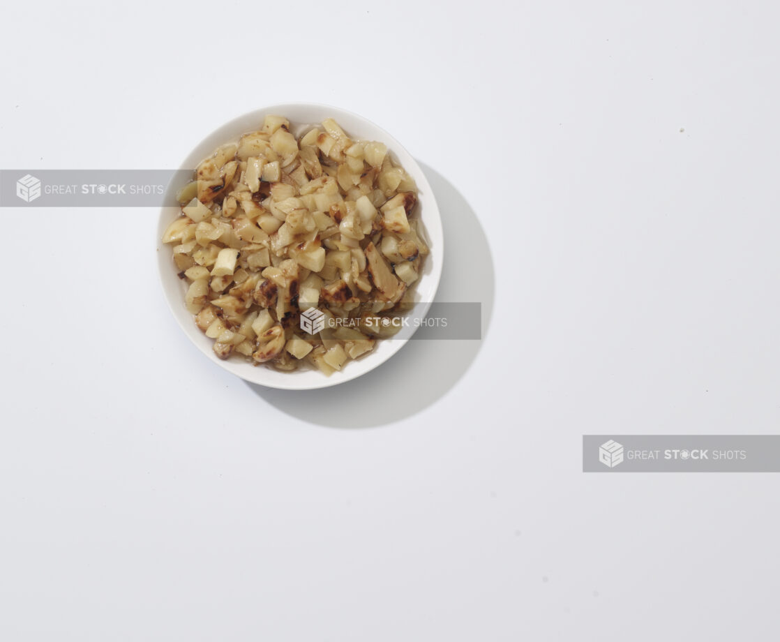 A bowl of roasted garlic on a white background