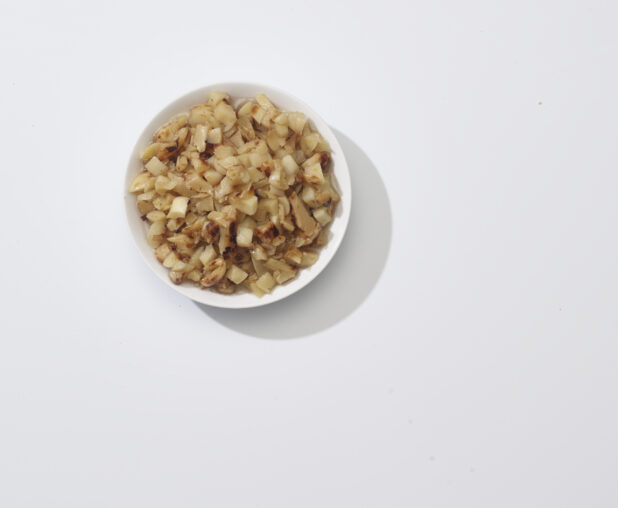 A bowl of roasted garlic on a white background