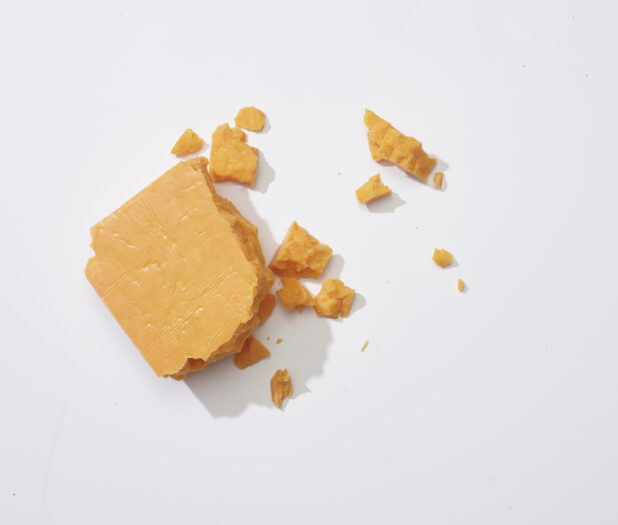 Crumbled aged cheddar cheese on a white background