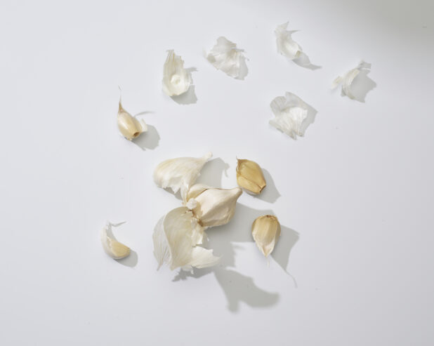 Bulb of garlic separated into cloves on a white background