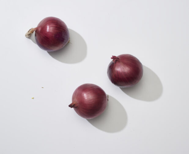 Whole red onions on a white background