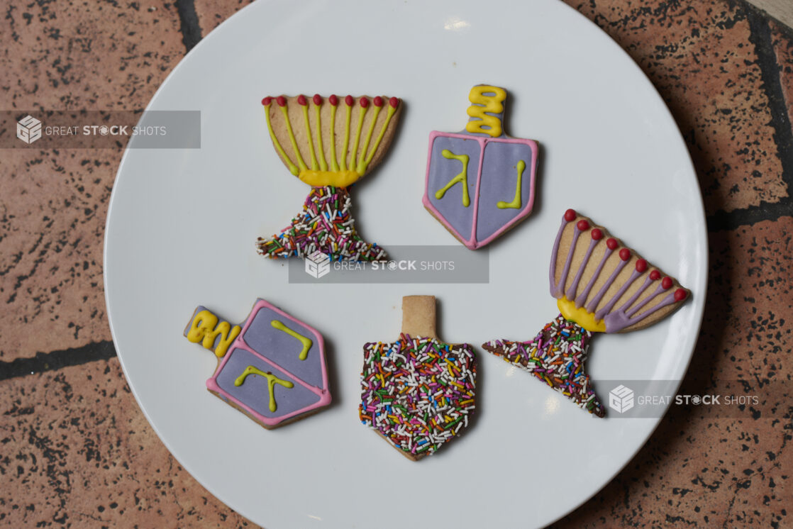 A plate of blue and yellowdecorative cookies with sprinkles on a tile background