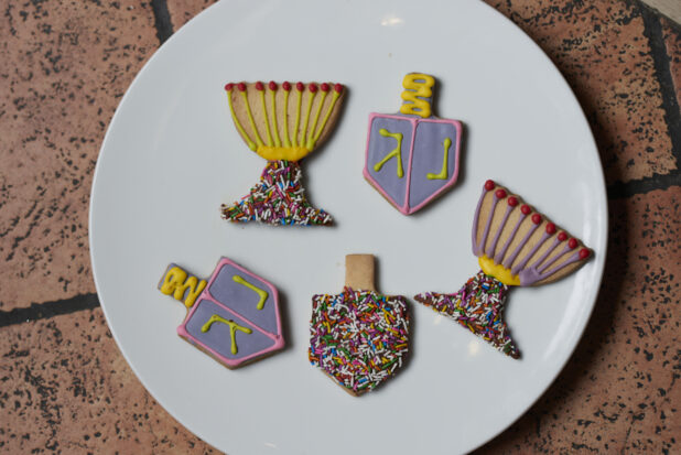 A plate of blue and yellowdecorative cookies with sprinkles on a tile background