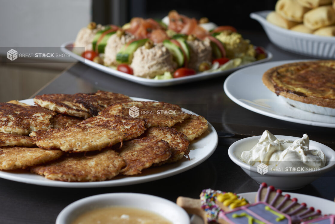 A buffet of Hanukkah food on a dark tabletop