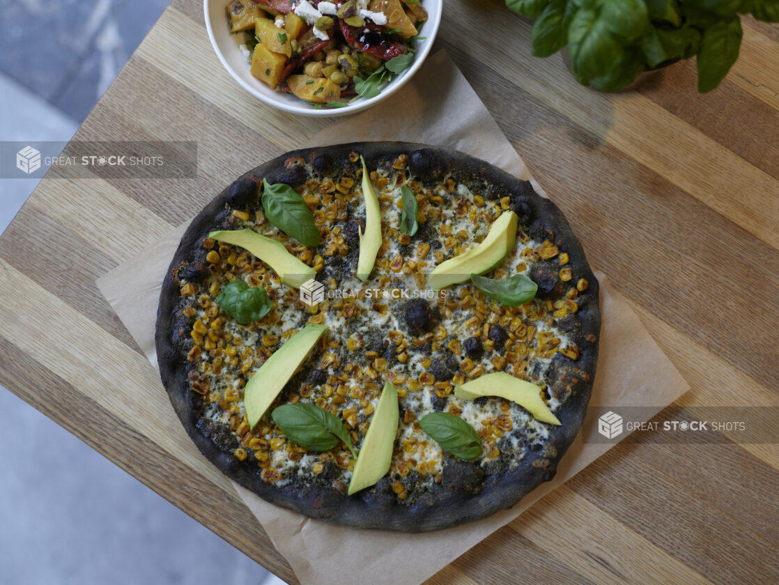 An Ikasumi California style pizza on parchment on a wooden table