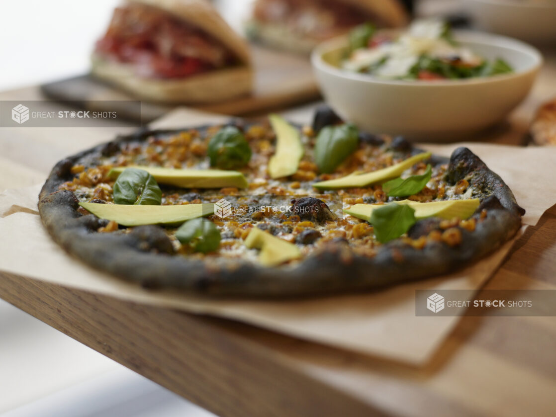 A Ikasumi California style pizza on parchment paper with side salad