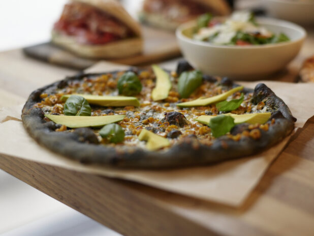 A Ikasumi California style pizza on parchment paper with side salad