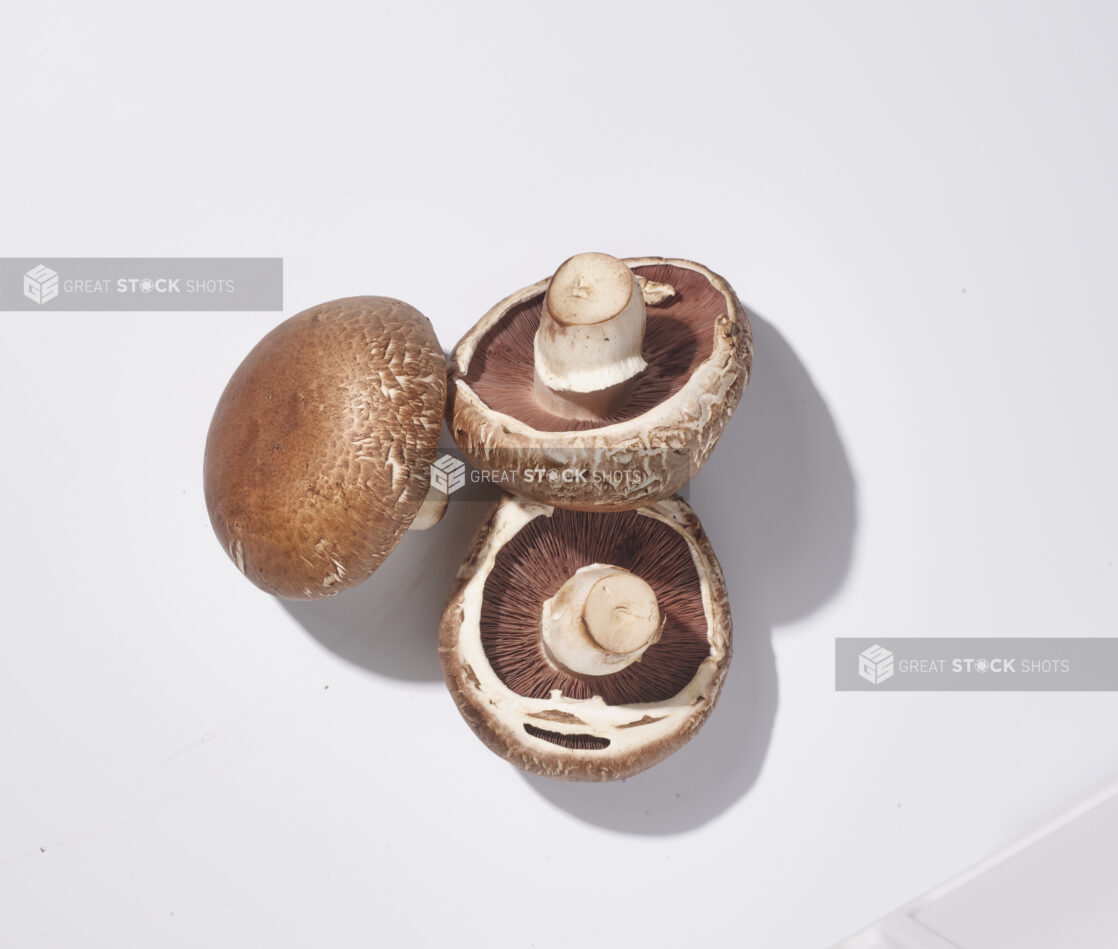 Whole fresh cremini mushrooms on a white background