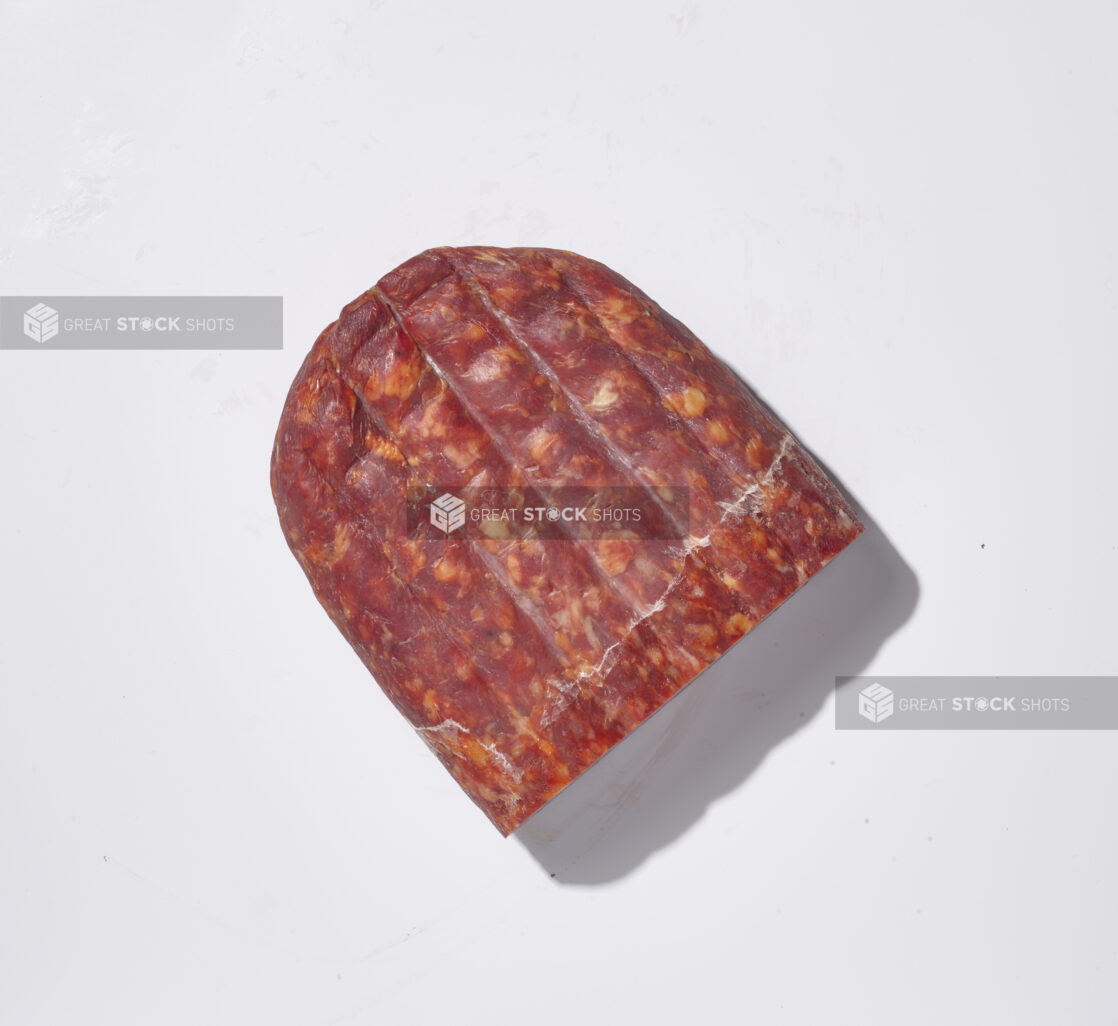 A whole piece of soppressata on a white background