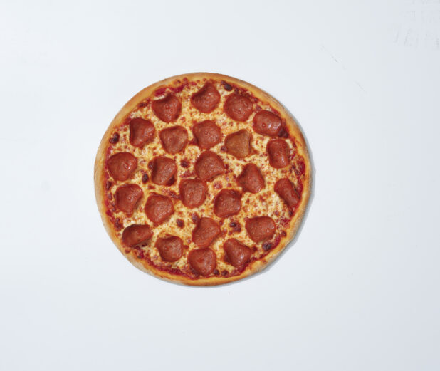 Whole unsliced Brooklyn style pepperoni pizza on a white background