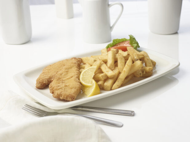 Battered fish and chips with lemon wedges on a white plate with a white background