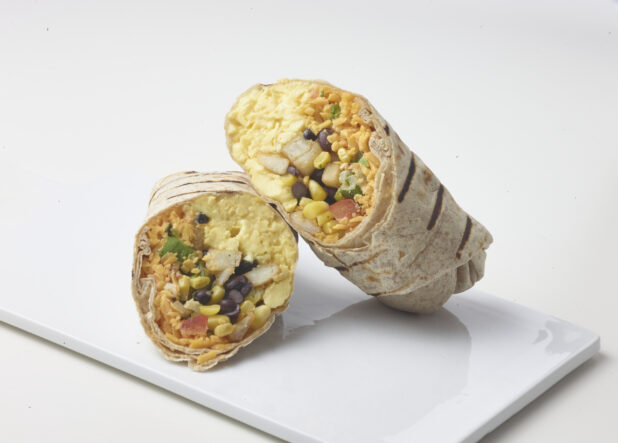 Breakfast burrito with scrambled eggs, potatoes, black beans, corn, salsa and cheddar cut in half on a white plate on a white background