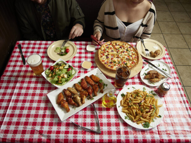 Couple at a restaurant with numerous dinner options on a red and white tablecloth in a restaurant
