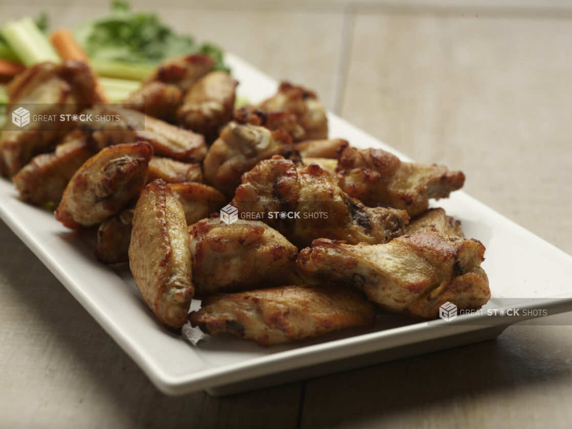 Naked chicken wings on a white plate on a wooden background