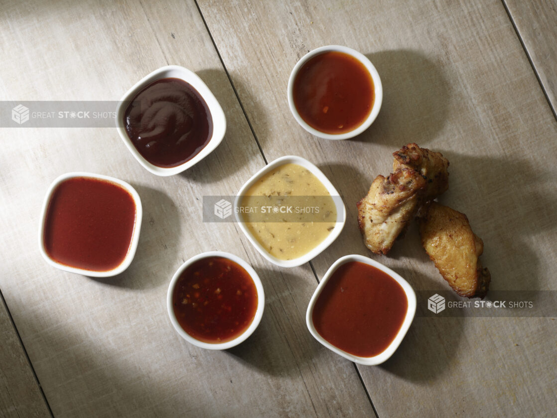 Overhead of various wing sauces for dipping on a wooden background