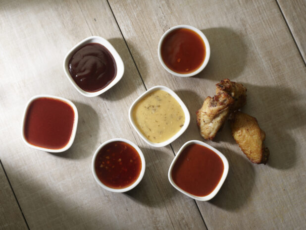 Overhead of various wing sauces for dipping on a wooden background