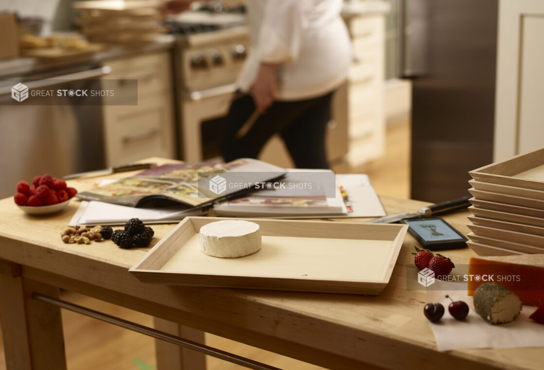 Chef preparing a wooden catering tray with cheese, fruit and nuts in a kitchen