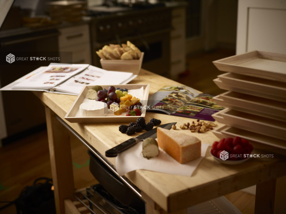 Preparing a wooden catering tray with cheese and fruit in a kitchen with instructions on a wooden table