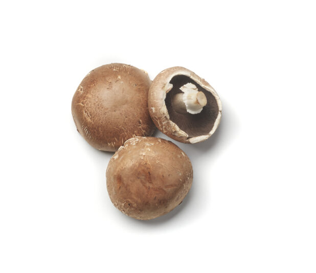 Whole cremini mushrooms on a white background