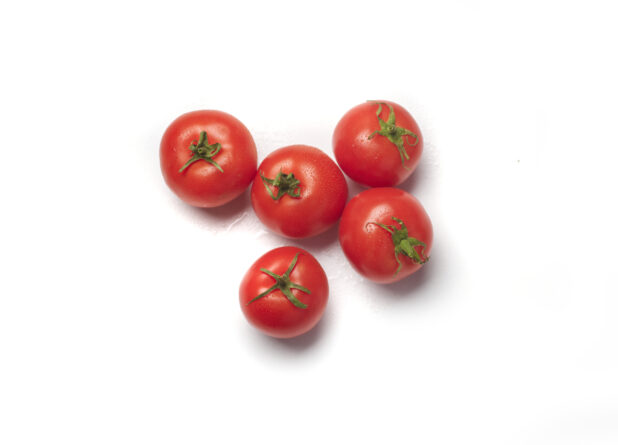 Five whole hothouse tomatoes with the pedicel and sepal showing on a white background