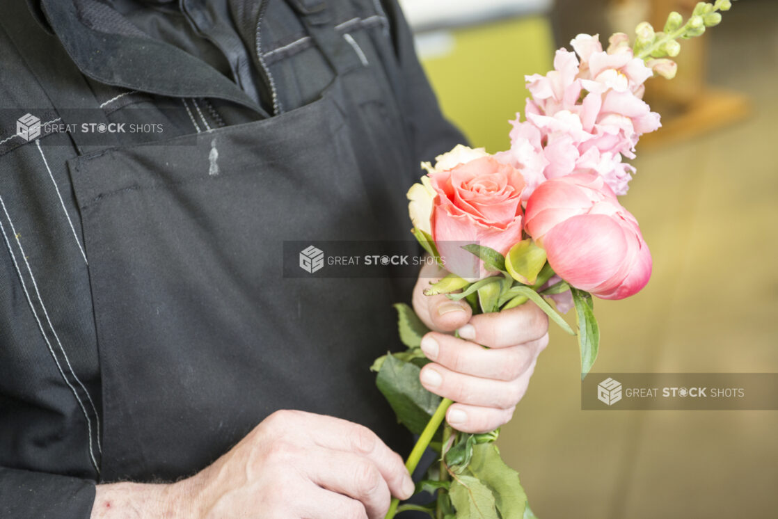 Florist holding an arrangement of monochromatic pink flowers