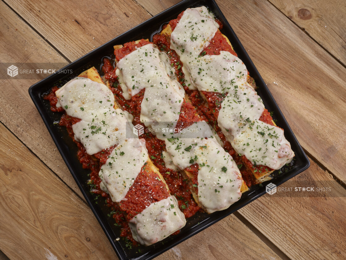 Lasagna displayed on a square black platter on a wooden background