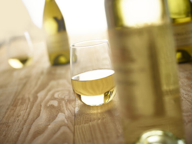 Bottles of white wine with glasses of white wine on a wooden background