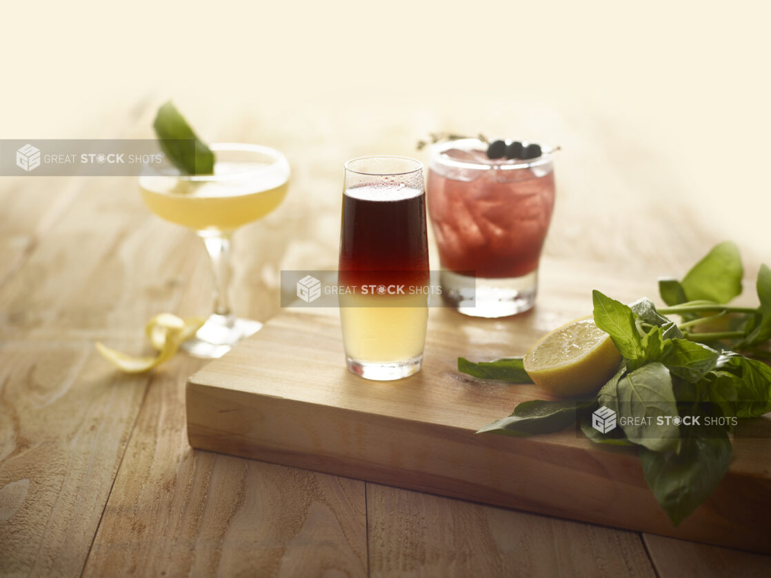 Cocktails with sliced lemon and fresh basil on a wooden board, on a wooden background