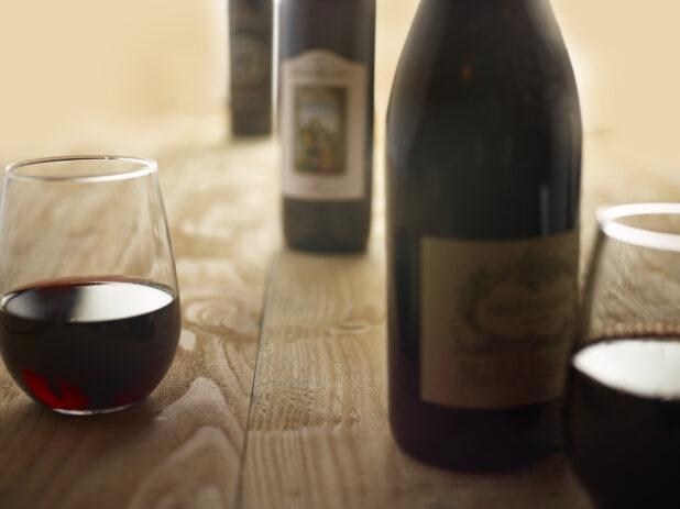 Bottles of Red wine with 2 glass of red wine on a wooden background