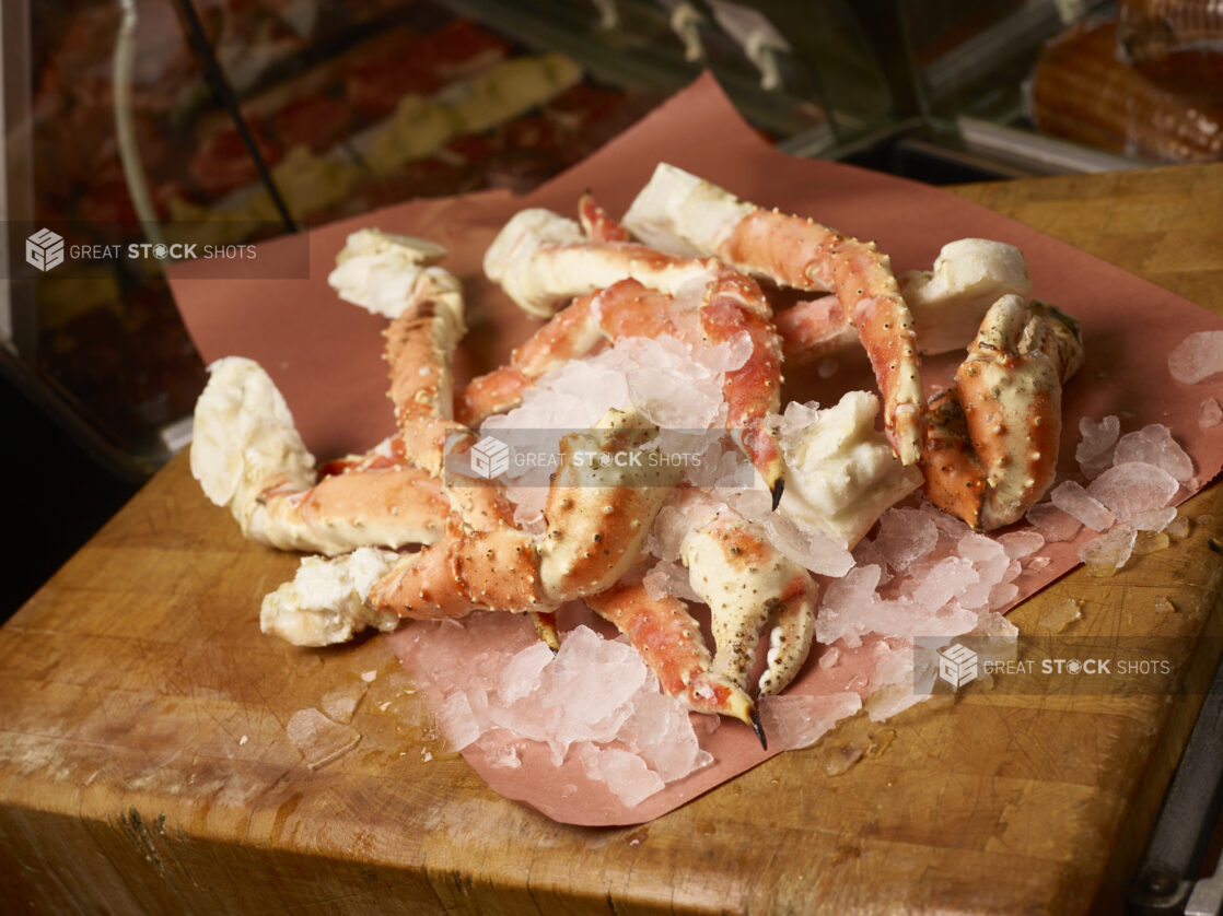 King crab legs on ice on butcher paper on a butcher block