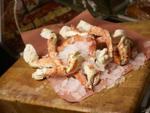 King crab legs on ice on butcher paper on a butcher block