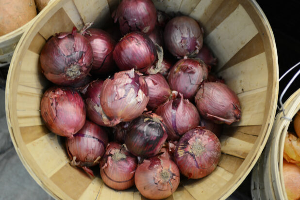 Whole raw red onions in a bushel basket, overhead view