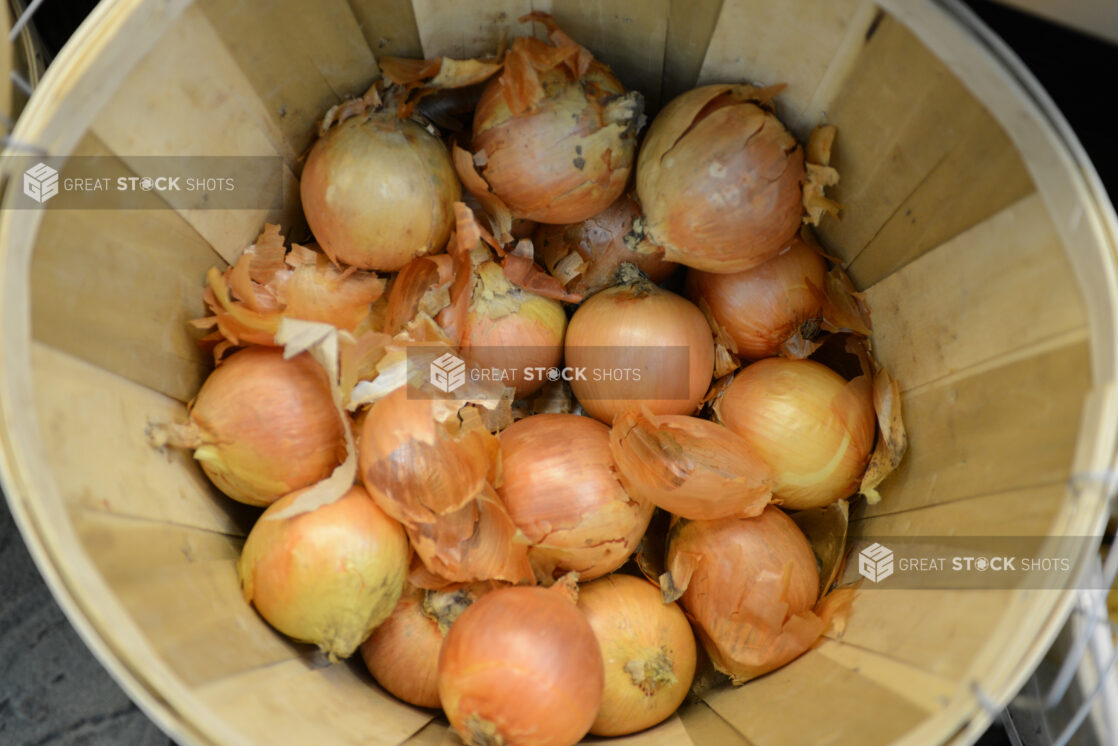 Whole raw onions in a bushel basket, overhead view