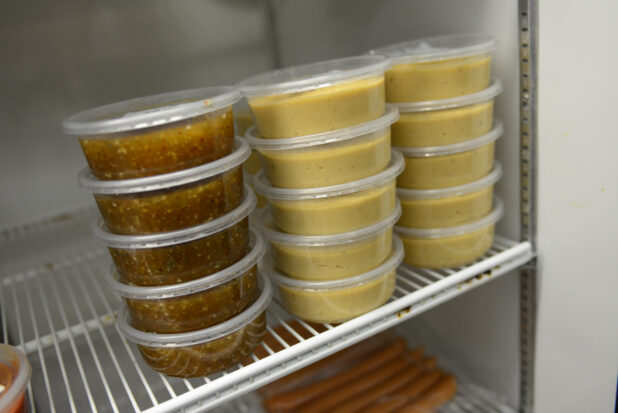 Dips and dressings in 8oz (250ml) clear plastic containers, stacked in a refrigerator