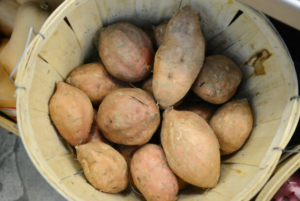 Whole sweet potatoes in a bushel basket, overhead view