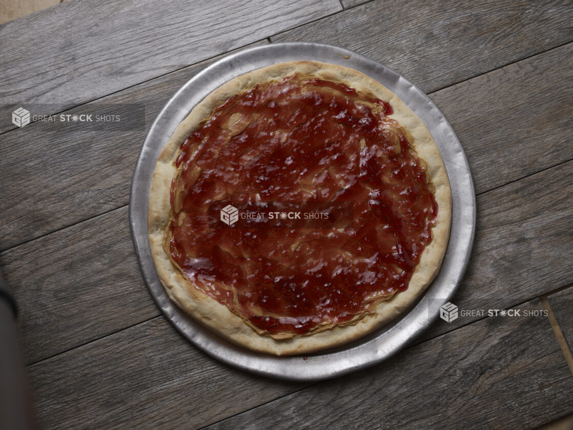 Overhead view of peanut butter and jam pizza on a wooden background