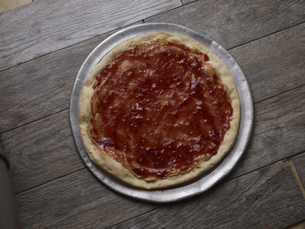 Overhead view of peanut butter and jam pizza on a wooden background