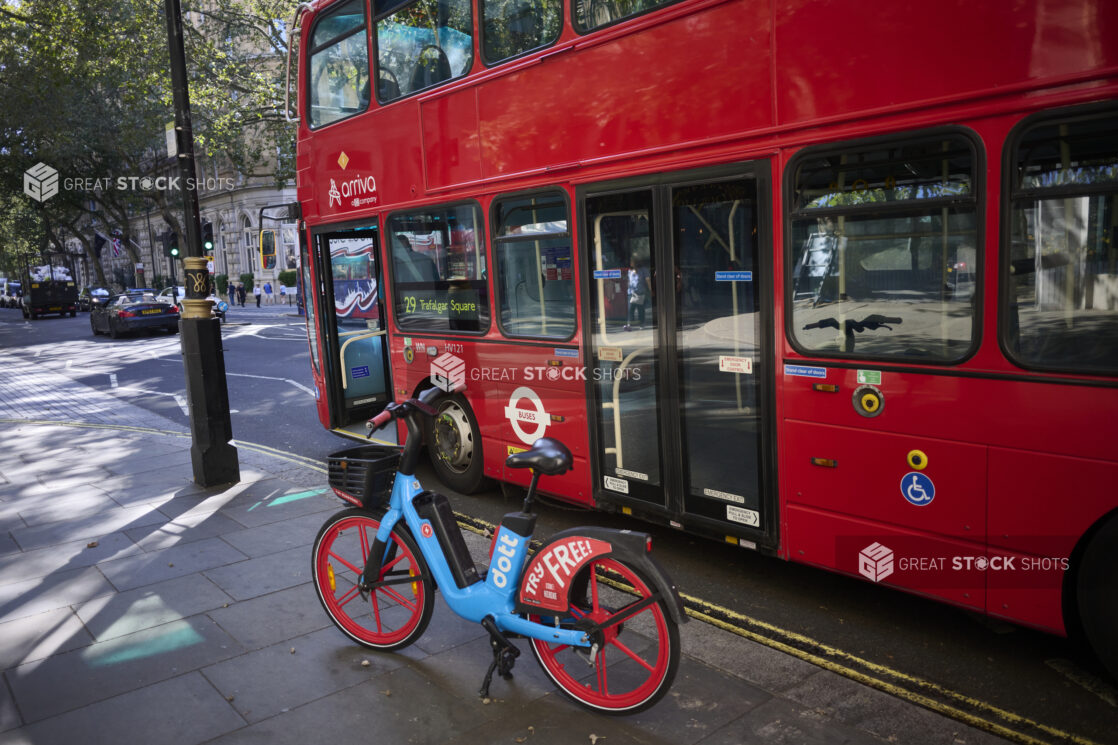 Double decker bus at a bus stop with a vibrant coloured e-bike next to it on a London, England road