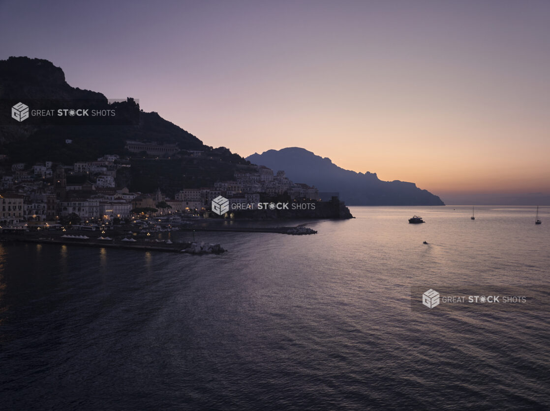 Sunrise/sunset view over the sea of a marina, town and hillside in Italy