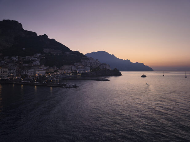 Sunrise/sunset view over the sea of a marina, town and hillside in Italy