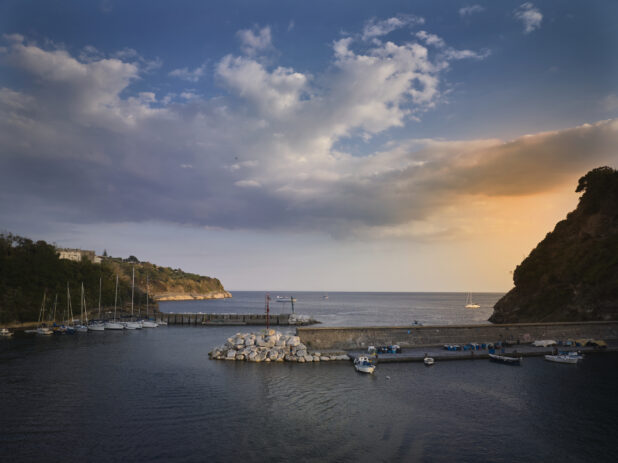 Sunset/sunrise view of a hills, marina, and outer harbour in Italy