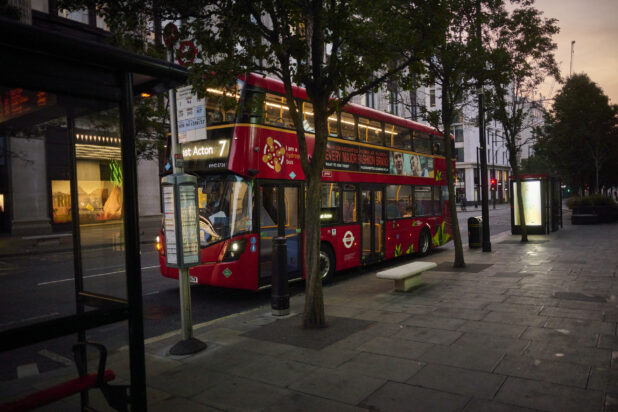 Double decker bus at a bus stop surrounded by trees and a bus shelter in London, England