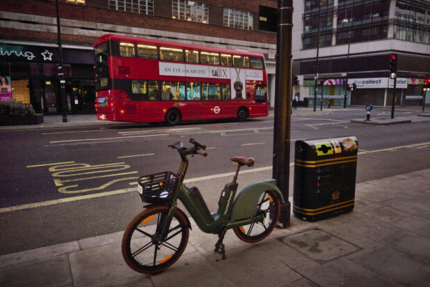 E-bike on a sidewalk across the street from a double decker bus in London, England