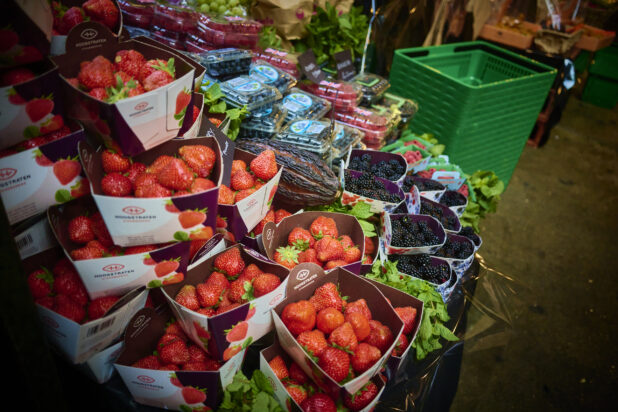 Close up of Fresh Whole Strawberries at a Market Stand - Assorted Berries in Background