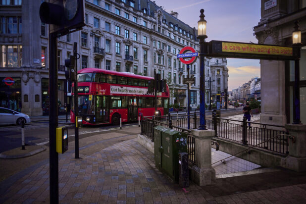 View of a tube (subway) station entrance with a double decker bus on the road and "Underground" street signs