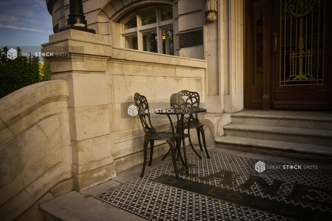 View of the entrance of Lanes of London restaurant with a small table and chairs out front