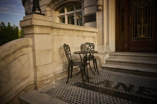 View of the entrance of Lanes of London restaurant with a small table and chairs out front